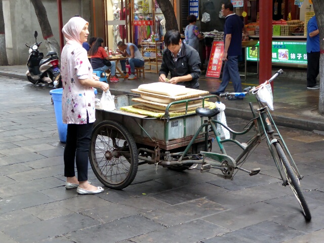 Lady buying tofu from the man with the bike